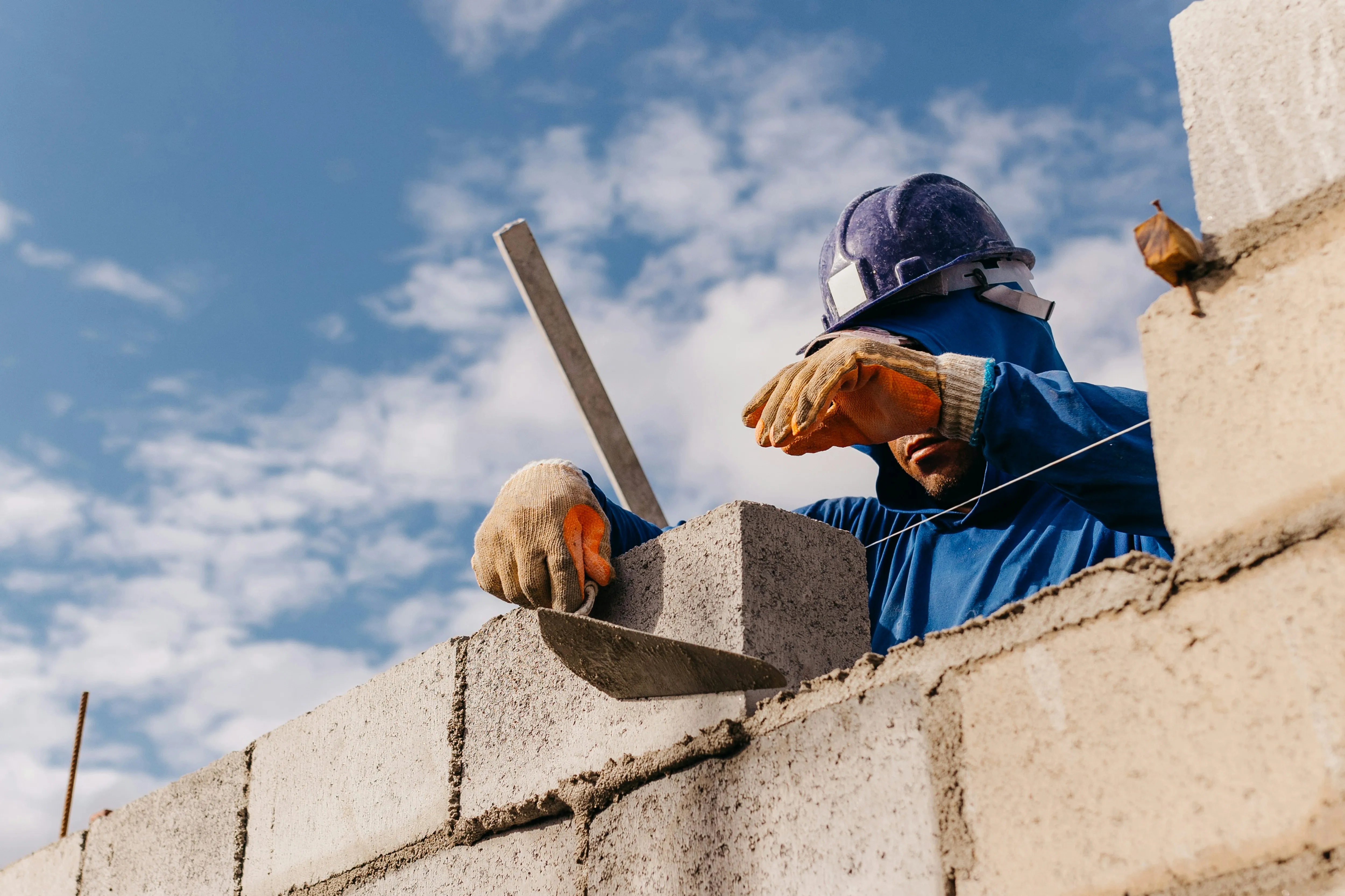 Builder laying concrete blocks with mortar