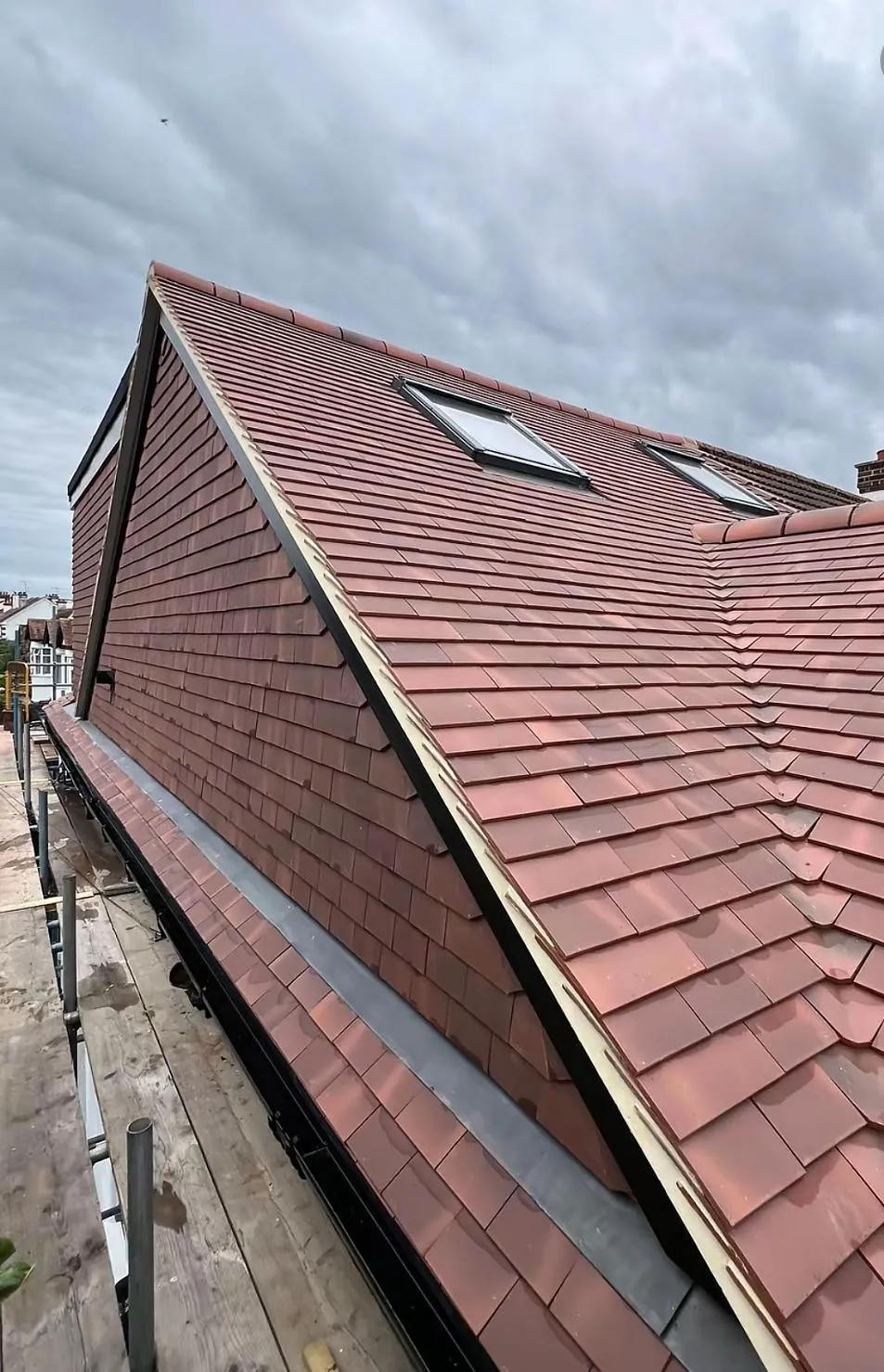 Newly installed terracotta tiled roof with integrated Velux windows and dark grey valley gutters by Devon and Cornwall Roofing