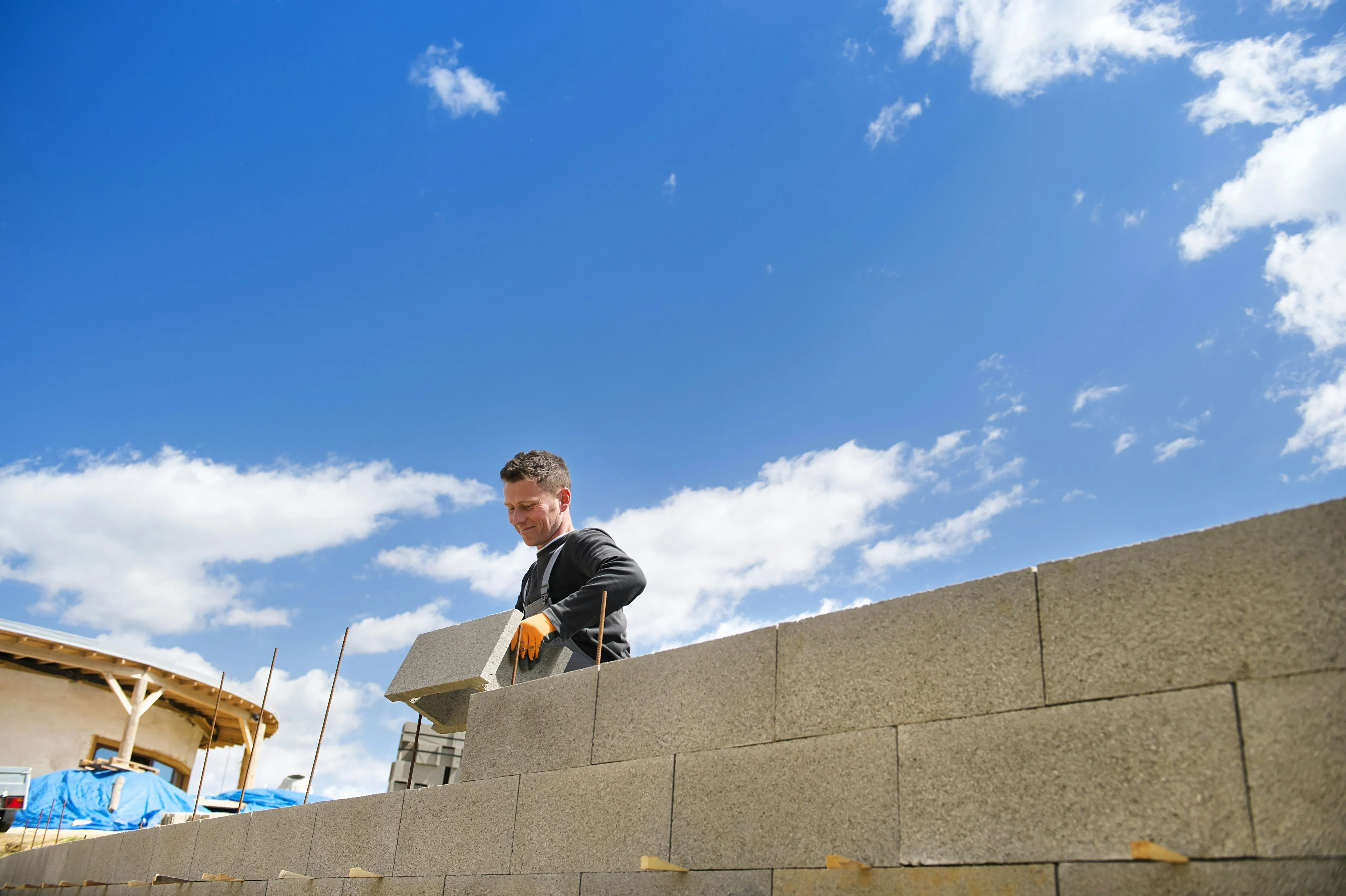 Construction worker laying concrete blocks for a new wall, demonstrating building services.