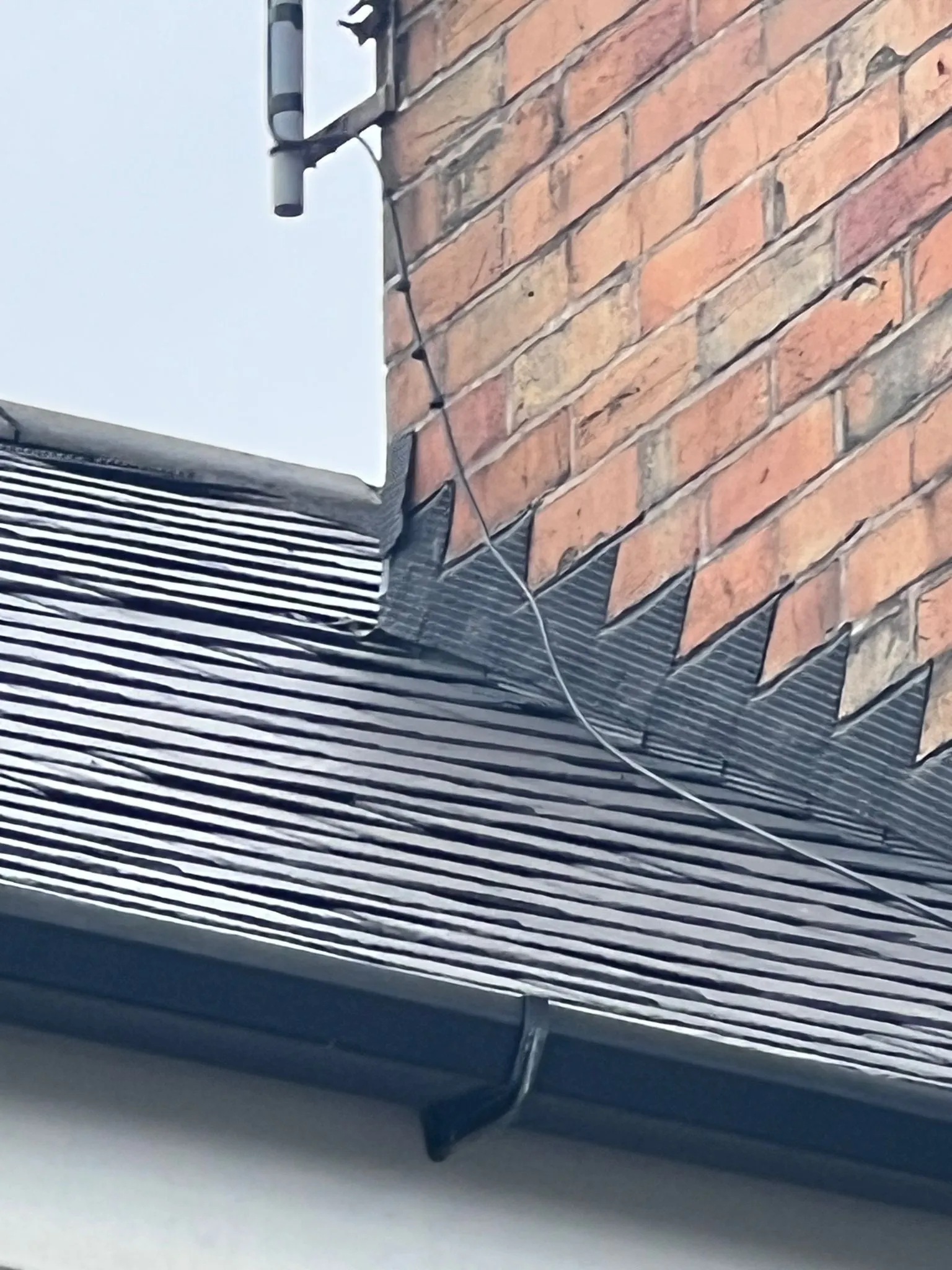Tiled roof meeting brick chimney with step flashing and guttering