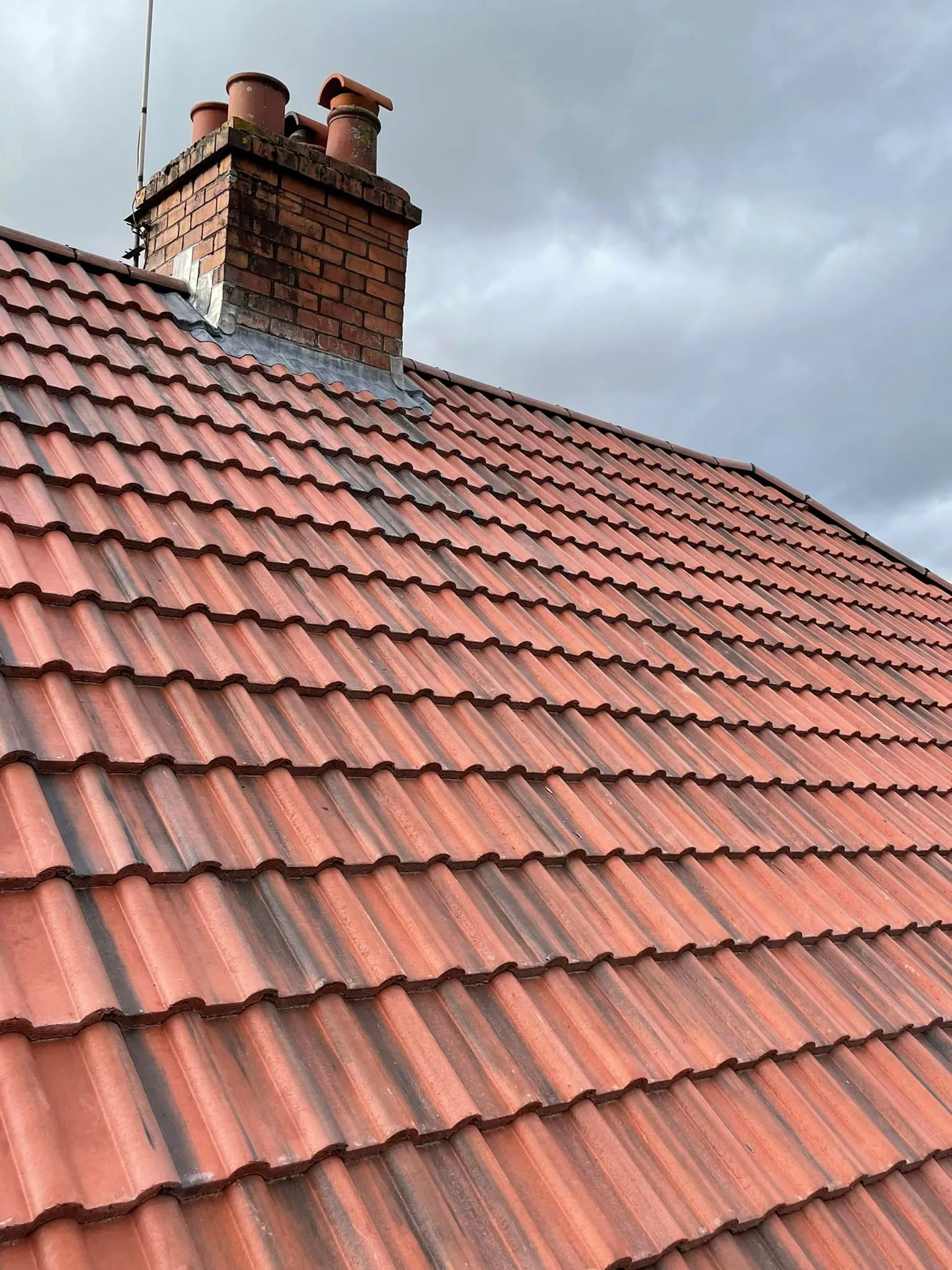 Weathered tiled roof and brick chimney needing repointing in Plymouth