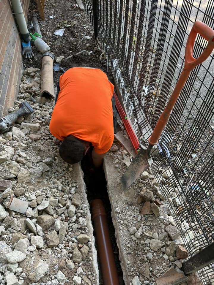 Drainage engineer working on an excavated drainage pipe in Torquay for installation or repair.
