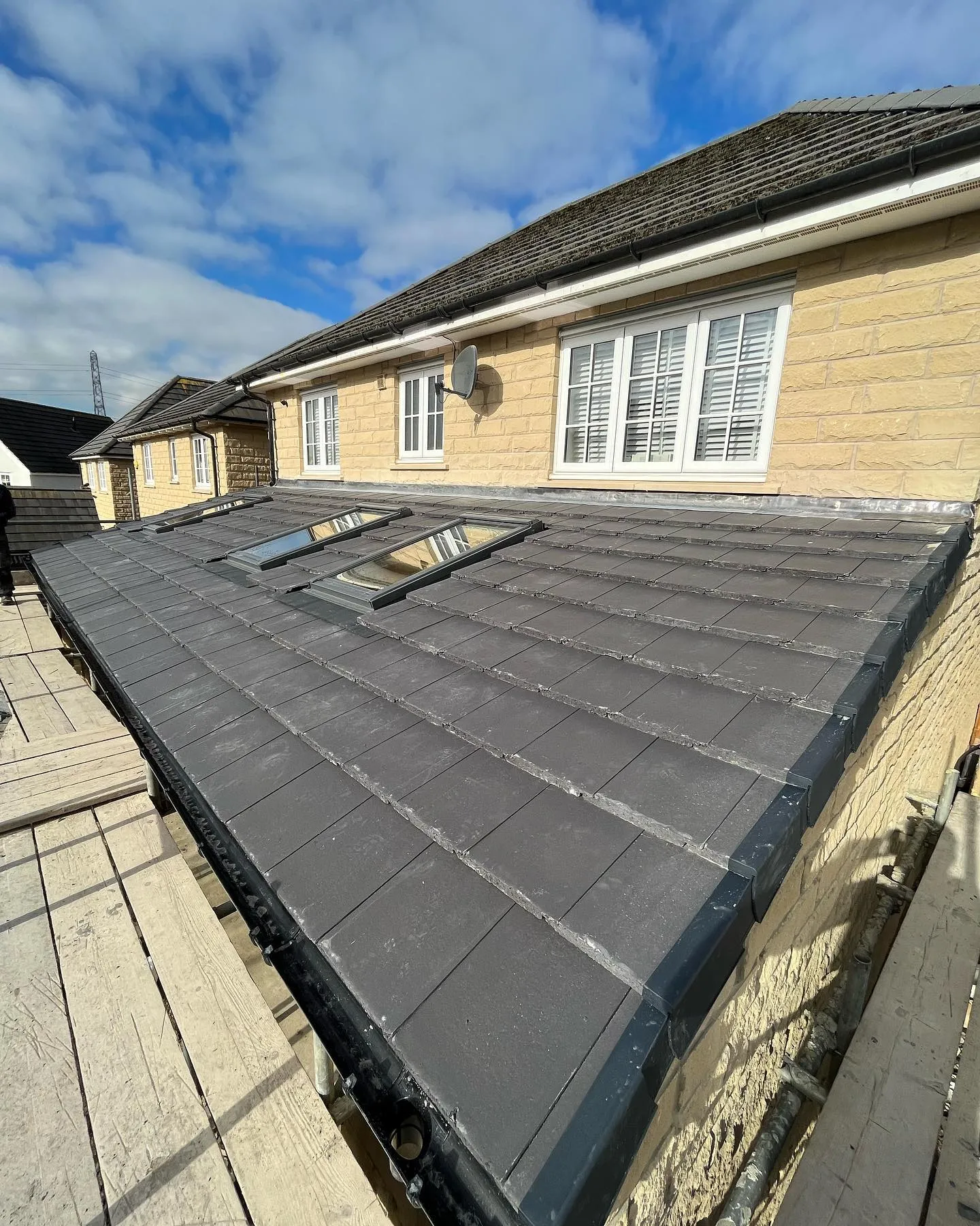 New pitched roof with grey tiles and multiple rooflights installed.