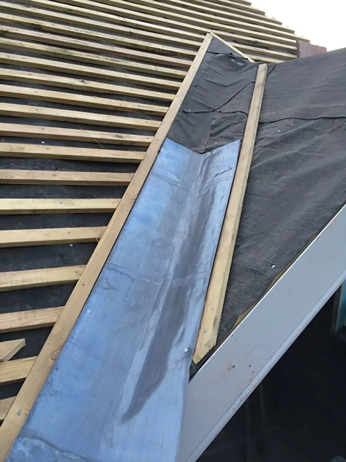 Lead flashing installation on a roof during construction or repair.