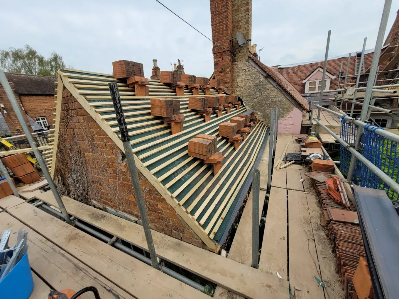 Re-roofing project showing roof membrane, battens, clay tiles, and scaffolding.