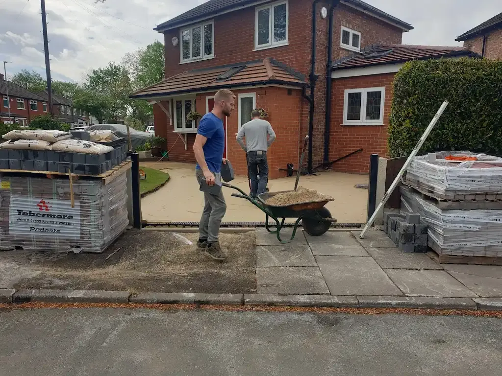 Workmen installing a driveway with paving blocks and materials