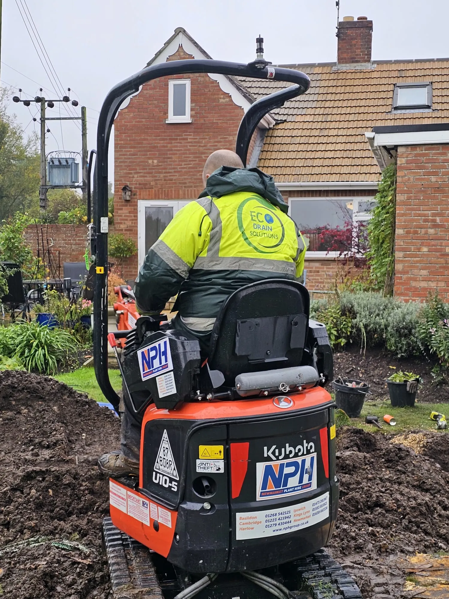 Eco Drain Solutions operative operating a mini-digger during groundworks for drainage installation at a residential property.