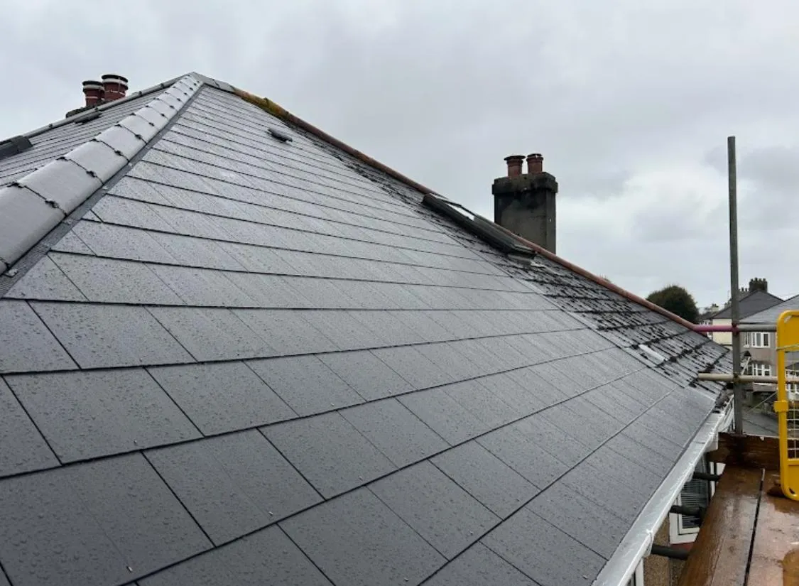 Newly fitted dark grey pitched roof with clean tiles or slates, showcasing expert re-roofing or new roof installation work.