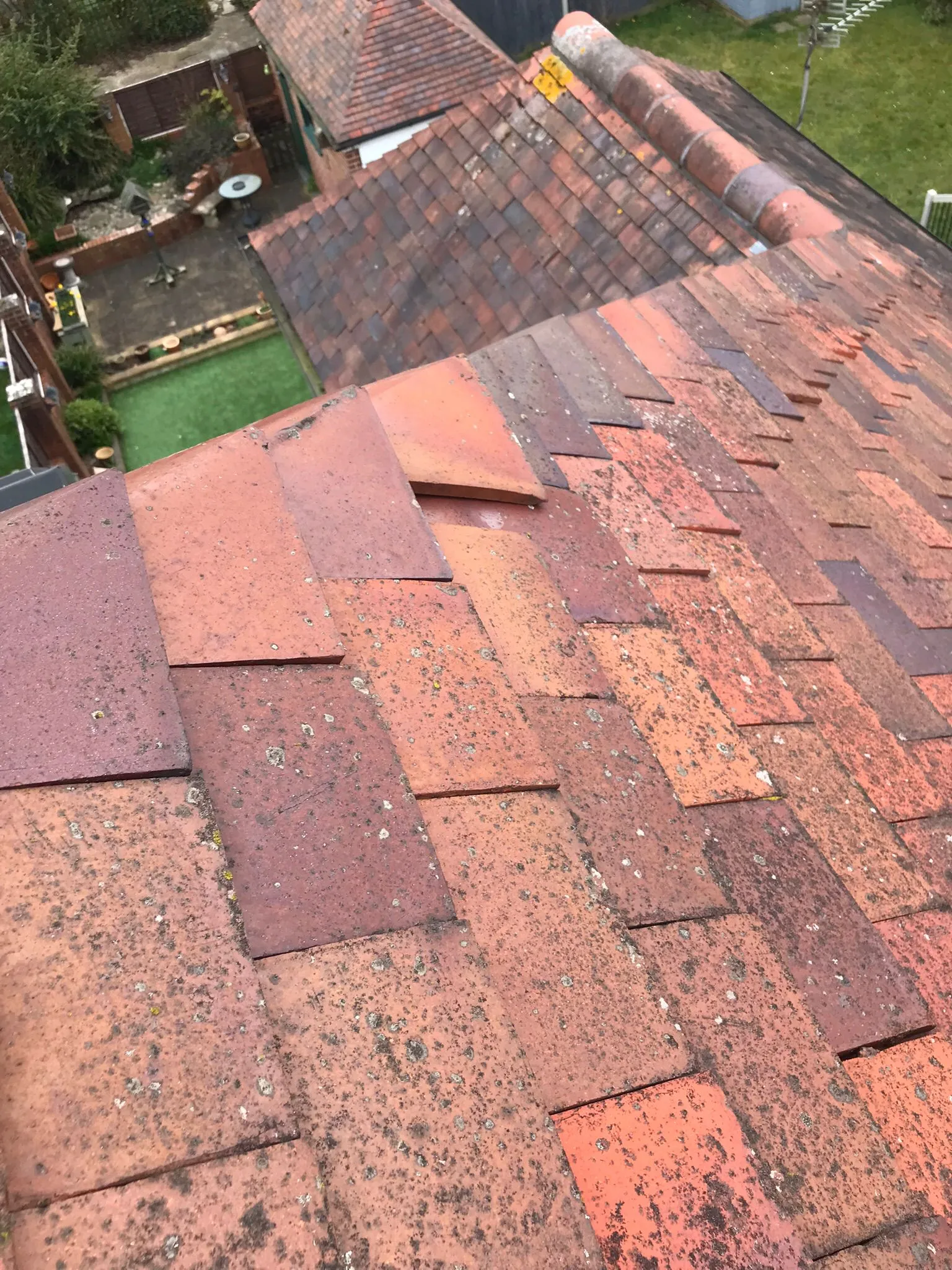 Damaged and moss-covered clay tiled roof with loose tiles, highlighting the need for professional roof repair.