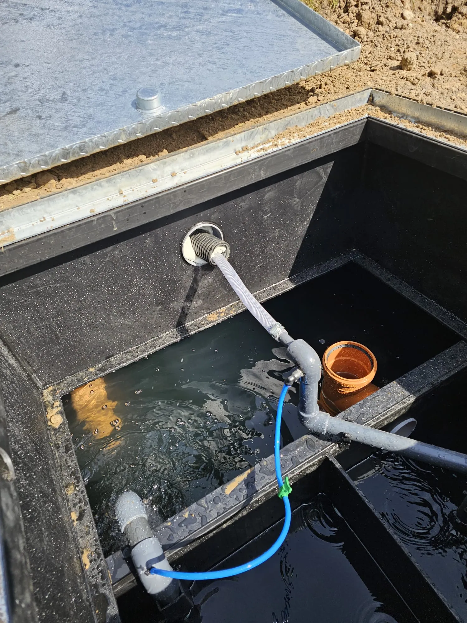 Inside a sewage treatment plant or septic tank with visible pipes and wastewater, during installation or a service check.