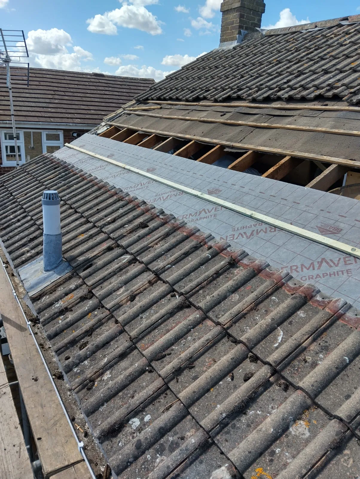 Residential roof being repaired or replaced, showing a mix of weathered tiles and modern roofing underlayment (Thermaven Graphite) with battens.