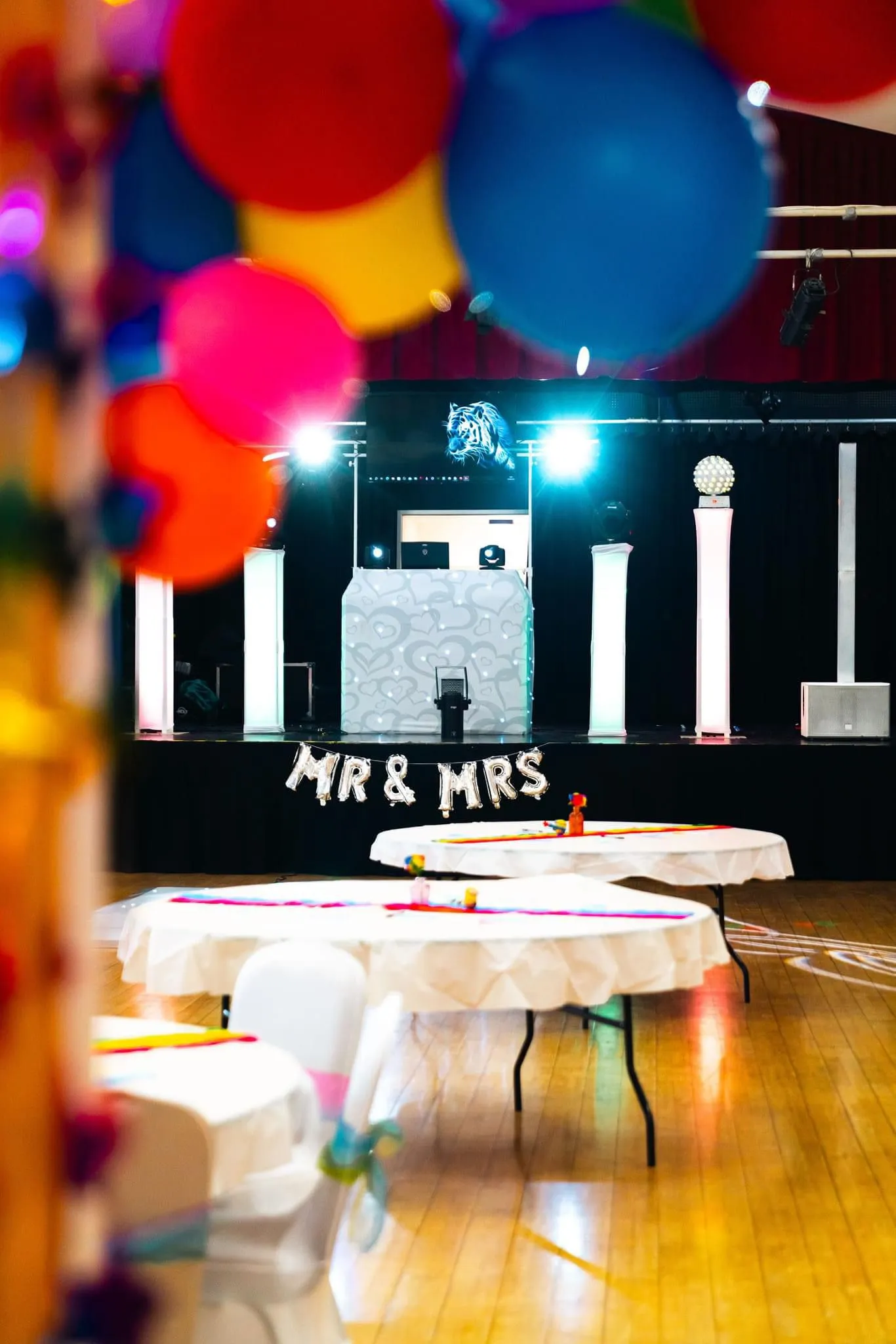 Professional wedding DJ setup with 'MR & MRS' balloons, modern sound and lighting, and a large screen for vibrant party entertainment.