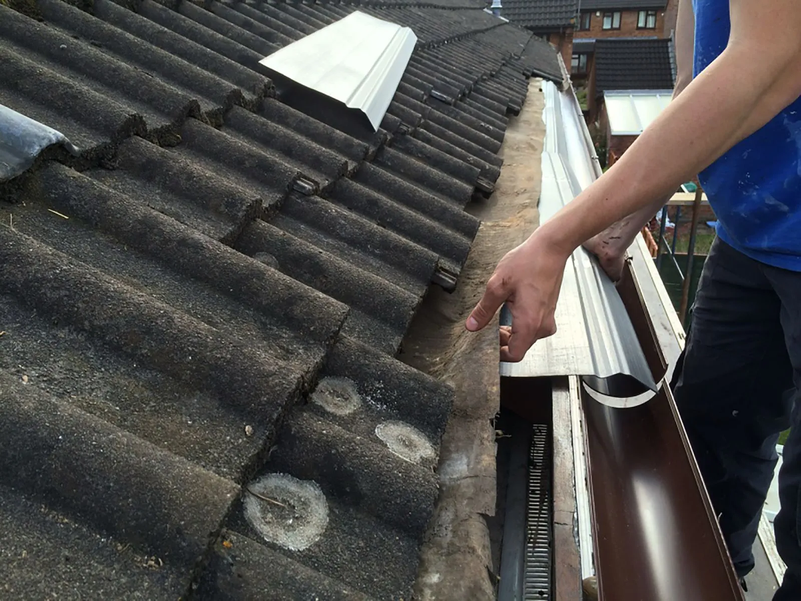Professional installing new guttering and flashing on a tiled roof.