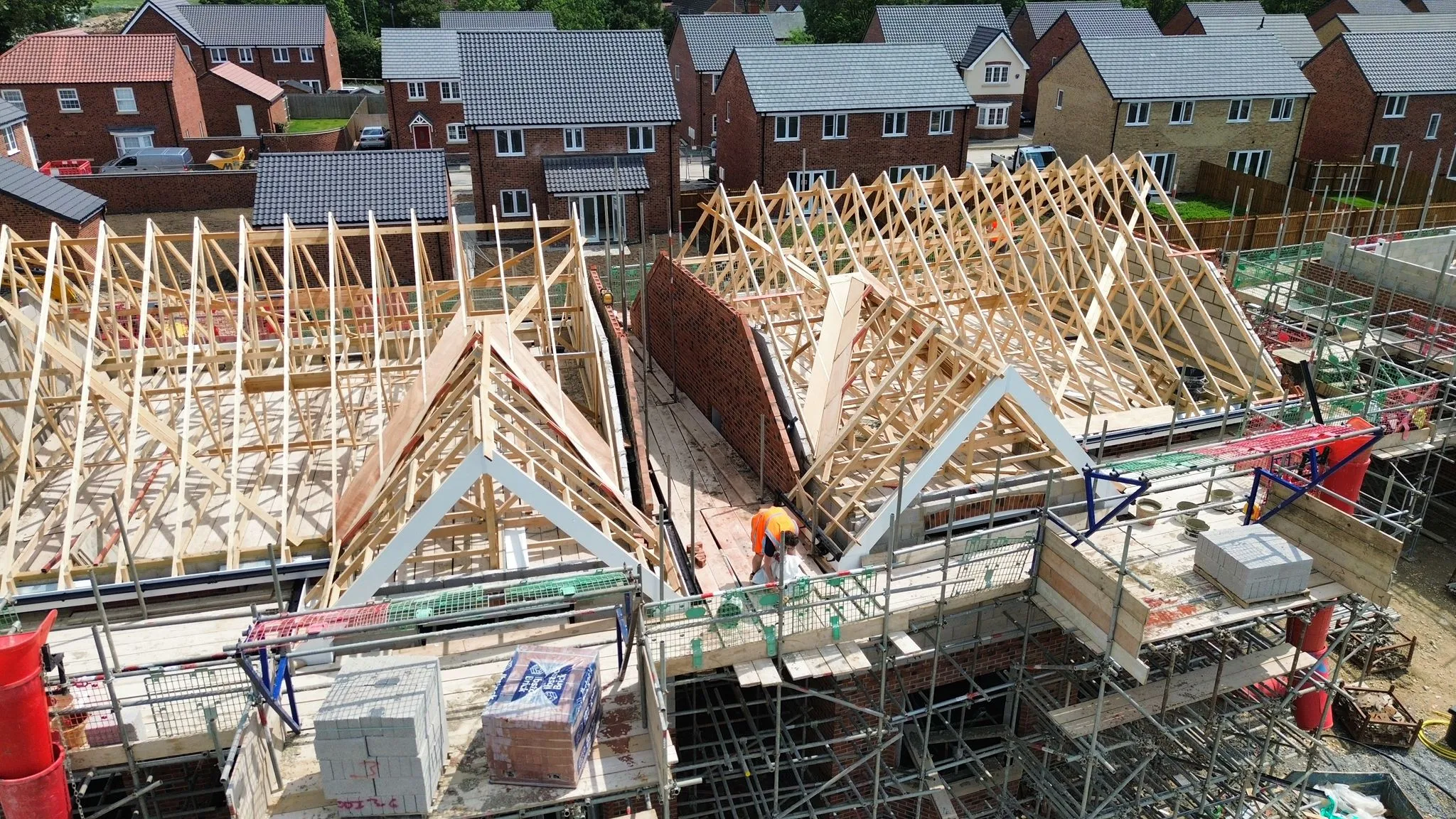 New build house roofs under construction, with wooden roof trusses and scaffolding visible, in a housing development near Spalding or Peterborough.