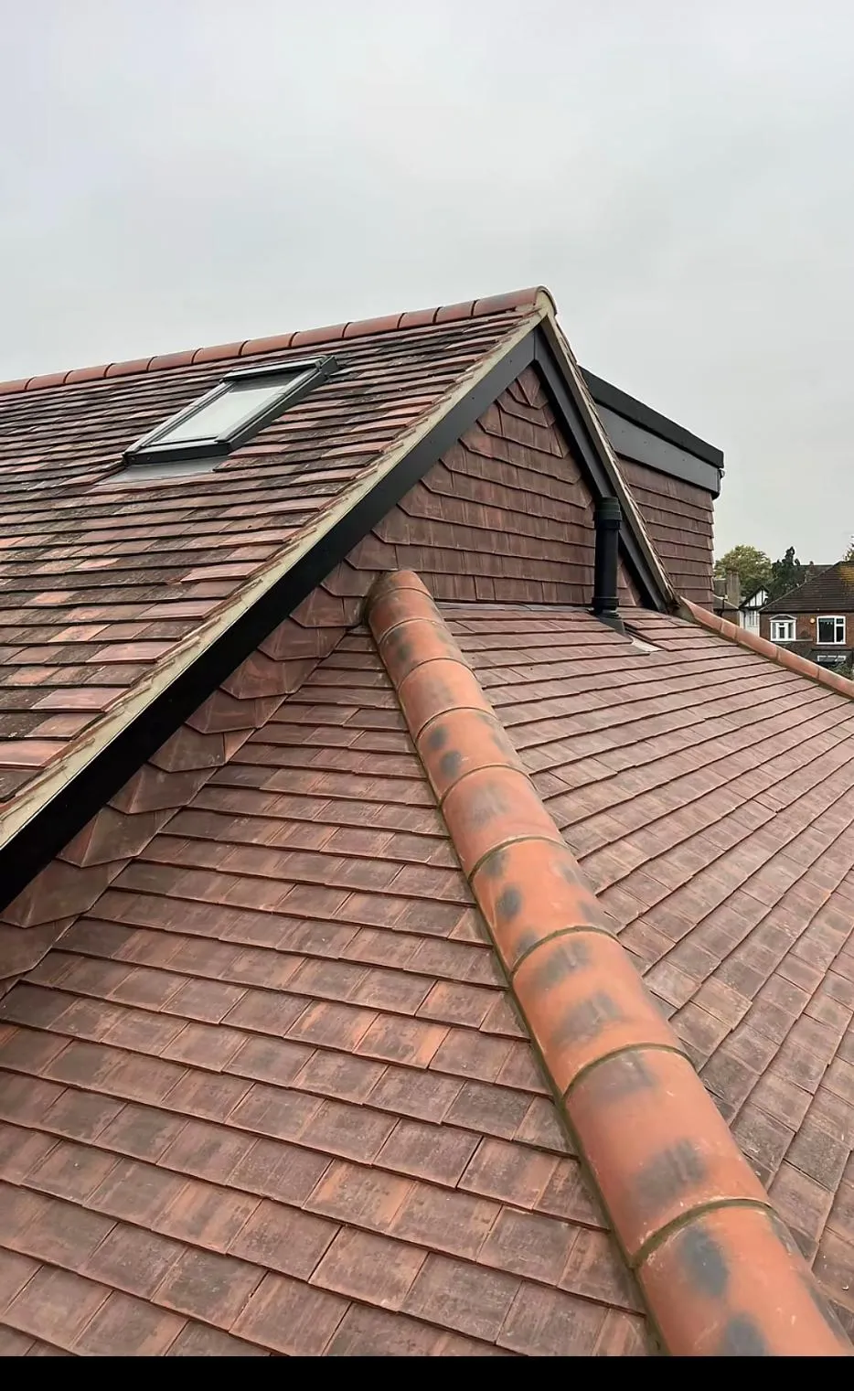 Newly installed tiled roof with a Velux window on a residential home.