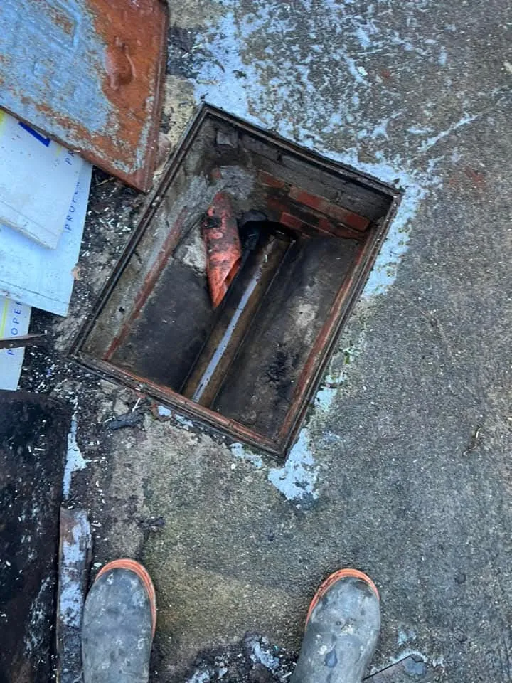 Open manhole cover showing a blocked drain pipe