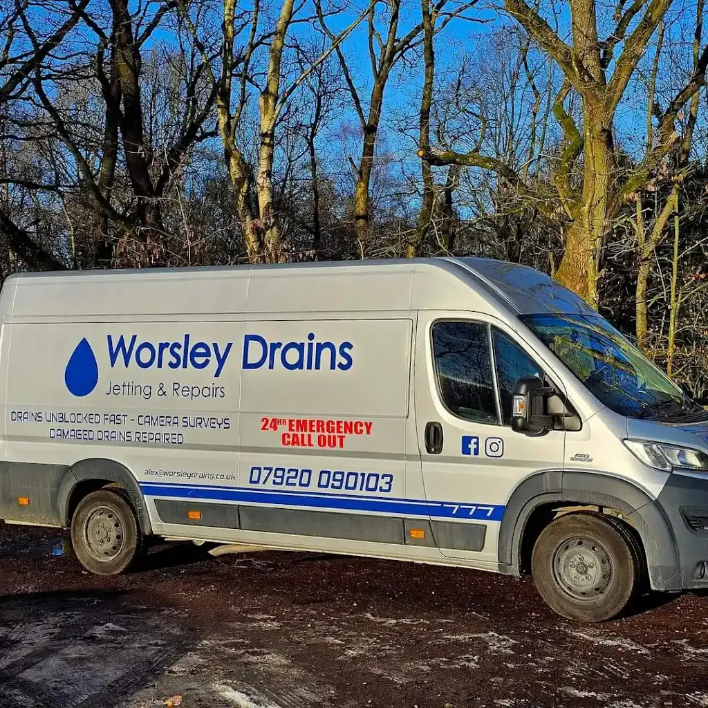A Worsley Drains branded service van, clearly showing the company name, logo, phone number [PHONENUMBERXXX], and services offered like drain jetting, repairs, and 24-hour emergency call-outs.
