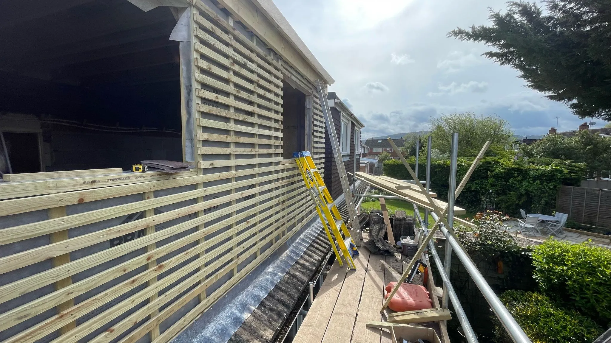 Scaffolding around a house extension in Hatherley with wooden battens being fitted by DP Carpentry & Building LTD.