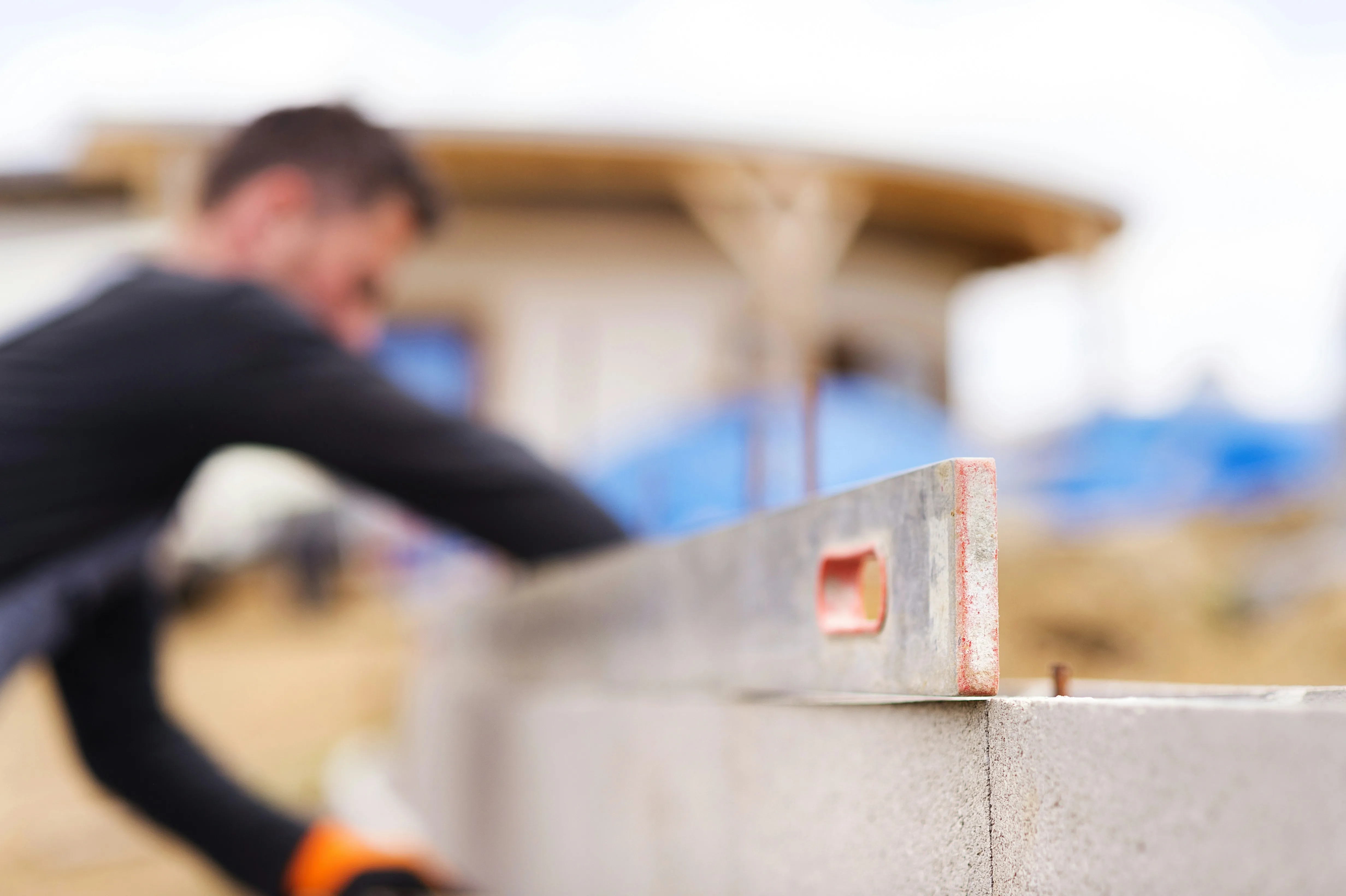 Close-up of a builder using a spirit level on a grey concrete block wall, ensuring it is perfectly straight during construction.