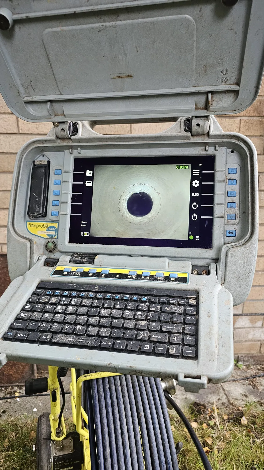 A close-up of a Flexiprobe P540c CCTV drain camera system with its screen showing the inside of a pipe.