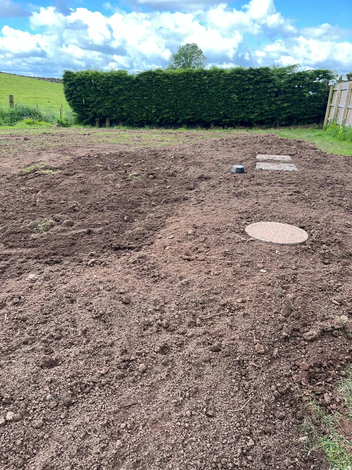 Disturbed ground with manhole covers for a drainage or septic system after installation