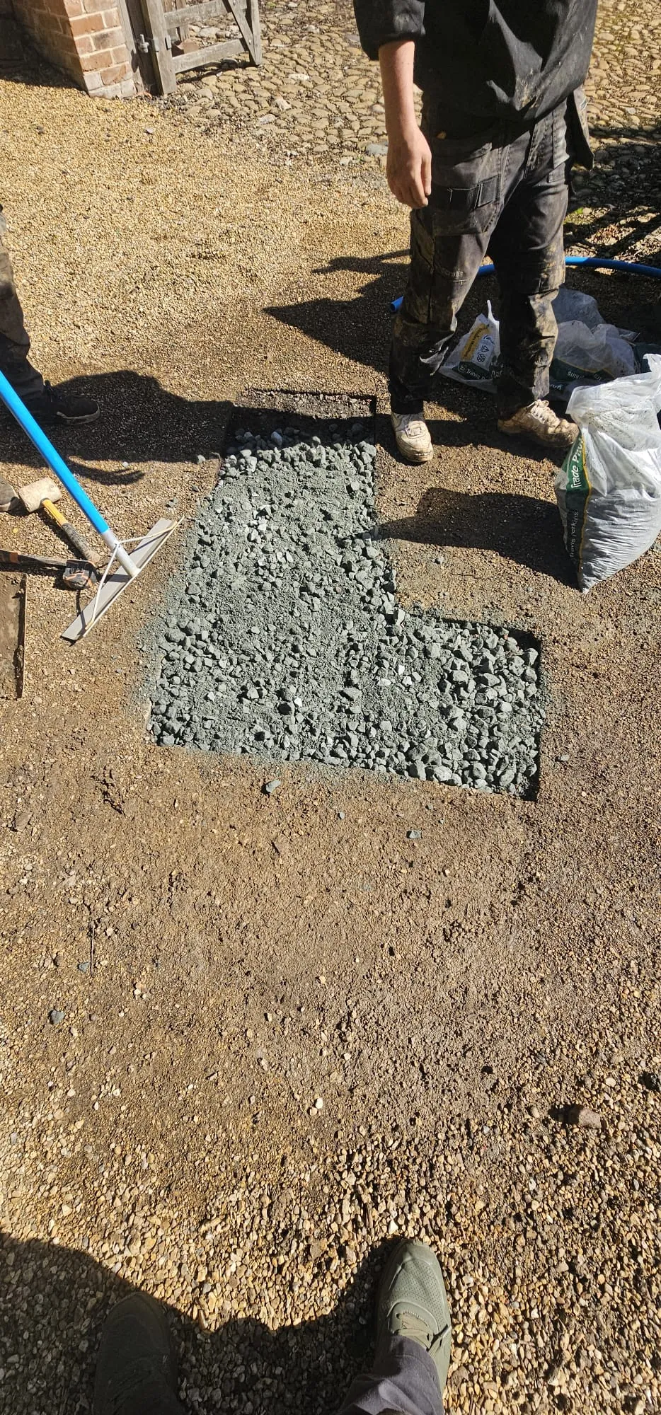 Groundworks team laying aggregate for drainage installation or soakaway base.