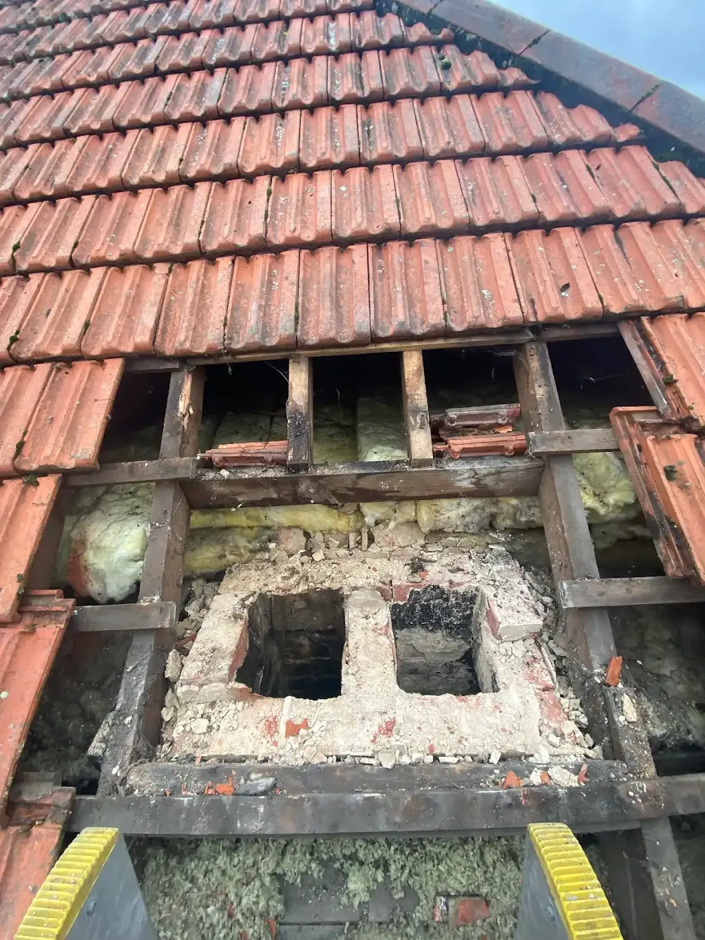 Damaged tiled roof and crumbling chimney stack in need of repair