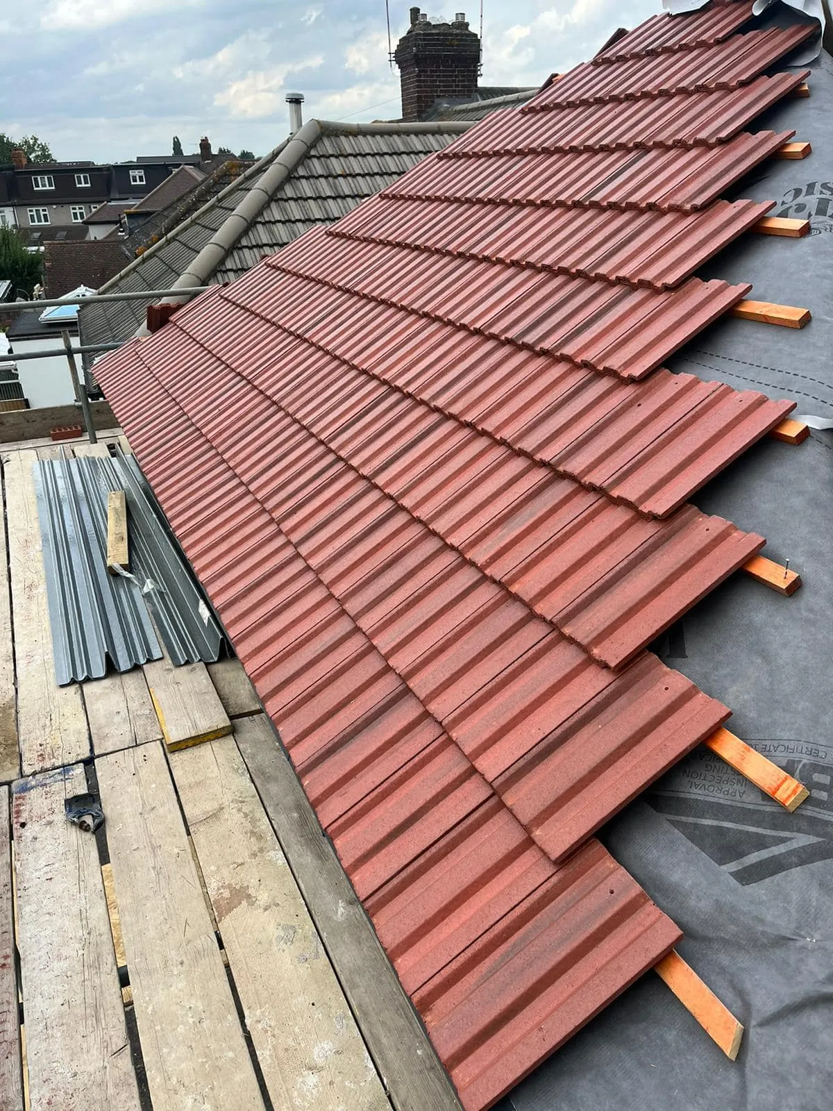 New concrete roof tile installation on a pitched roof with visible underlay and battens.