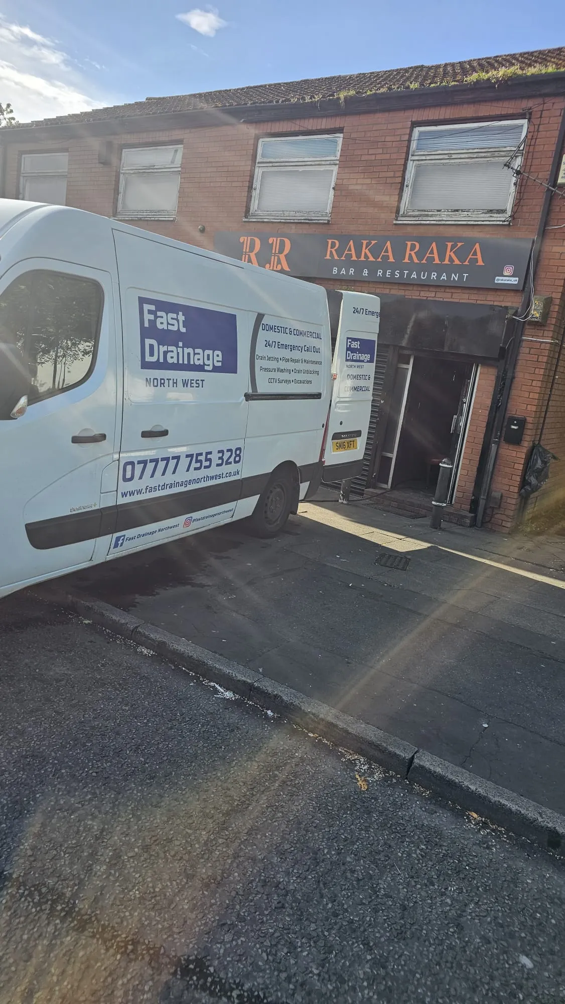 A Fast Drainage Northwest commercial service van parked outside a bar and restaurant.