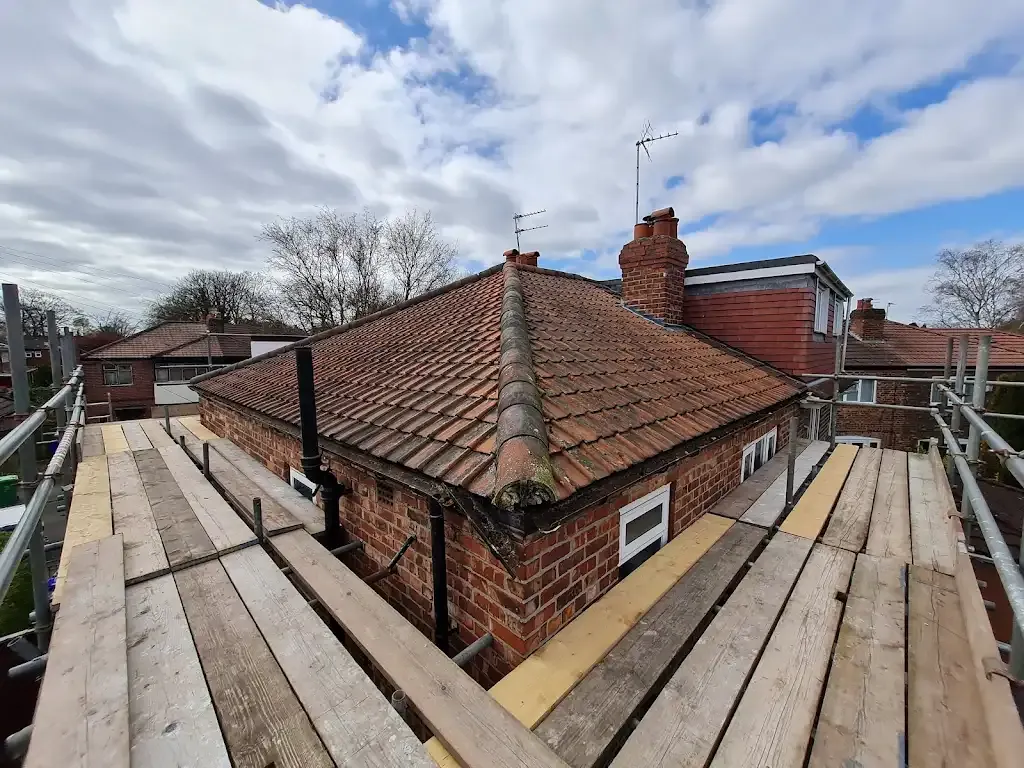 Scaffolding surrounding a tiled roof on a residential property, indicating roofing work in progress.