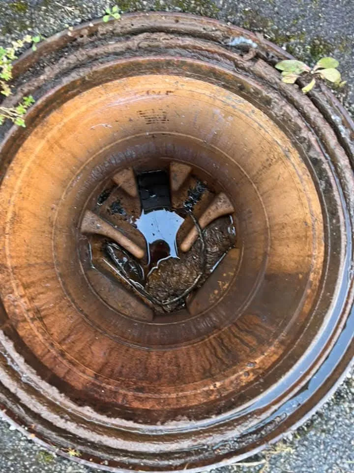 Open drain or manhole with water and debris.