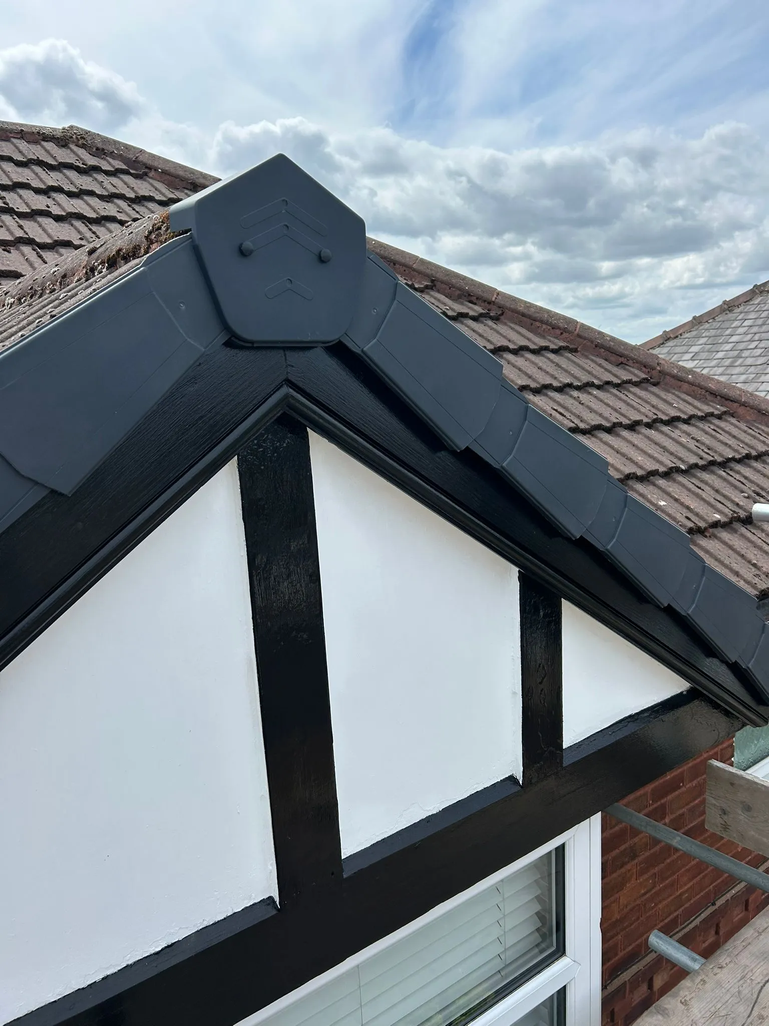 Newly installed dry verge system and refurbished black and white timber gable end on a pitched roof.