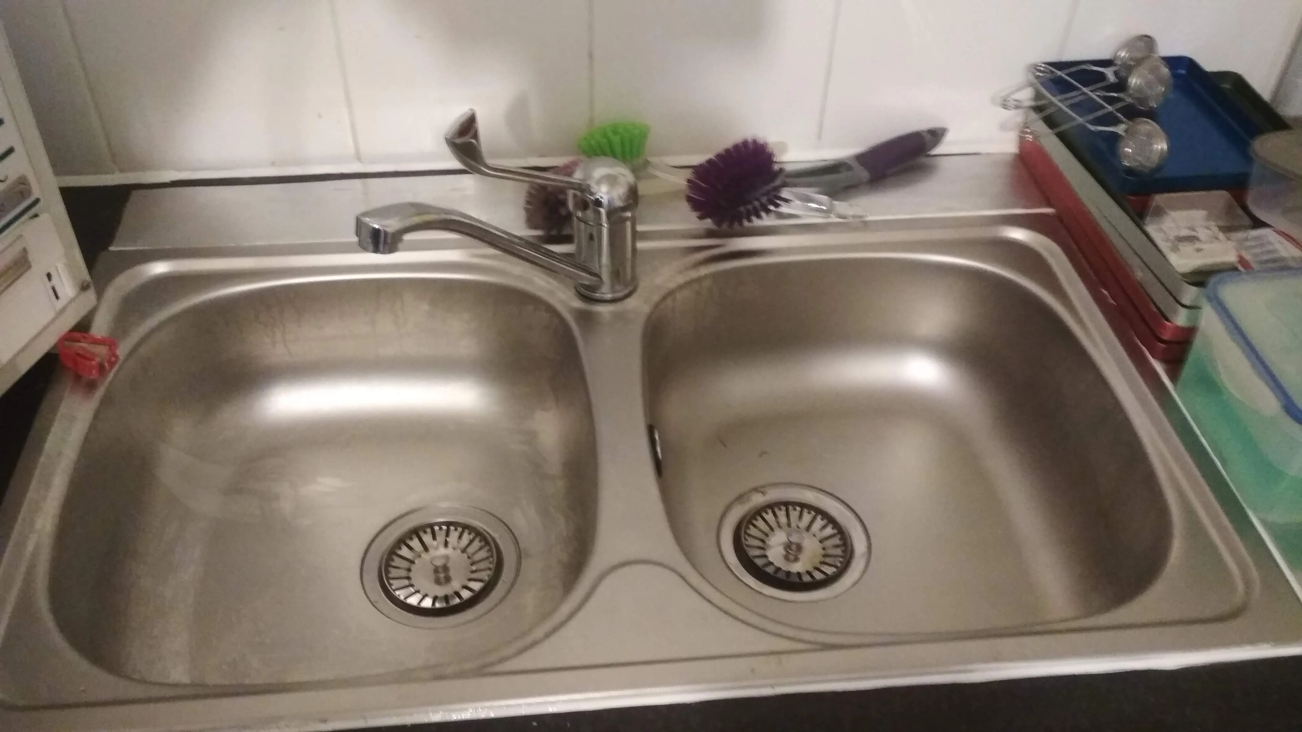 A double stainless steel kitchen sink with a tap