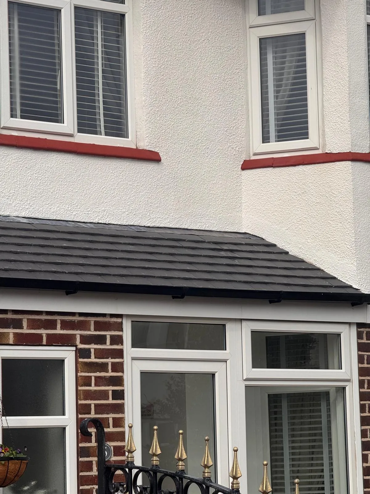 Newly installed or re-roofed dark grey slate or tile roof on a house extension or bay window, featuring new guttering.