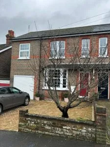 Two semi-detached brick houses with tiled roofs and a car in the driveway.