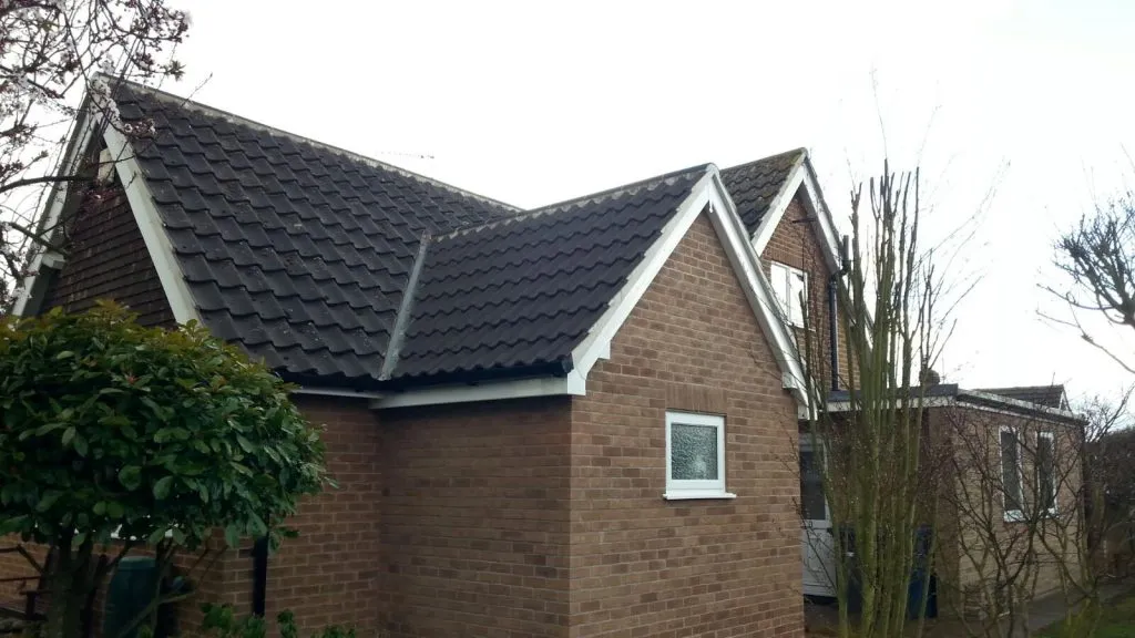 Exterior view of a house roof showing dark tiles, white fascias, soffits, and gutters.