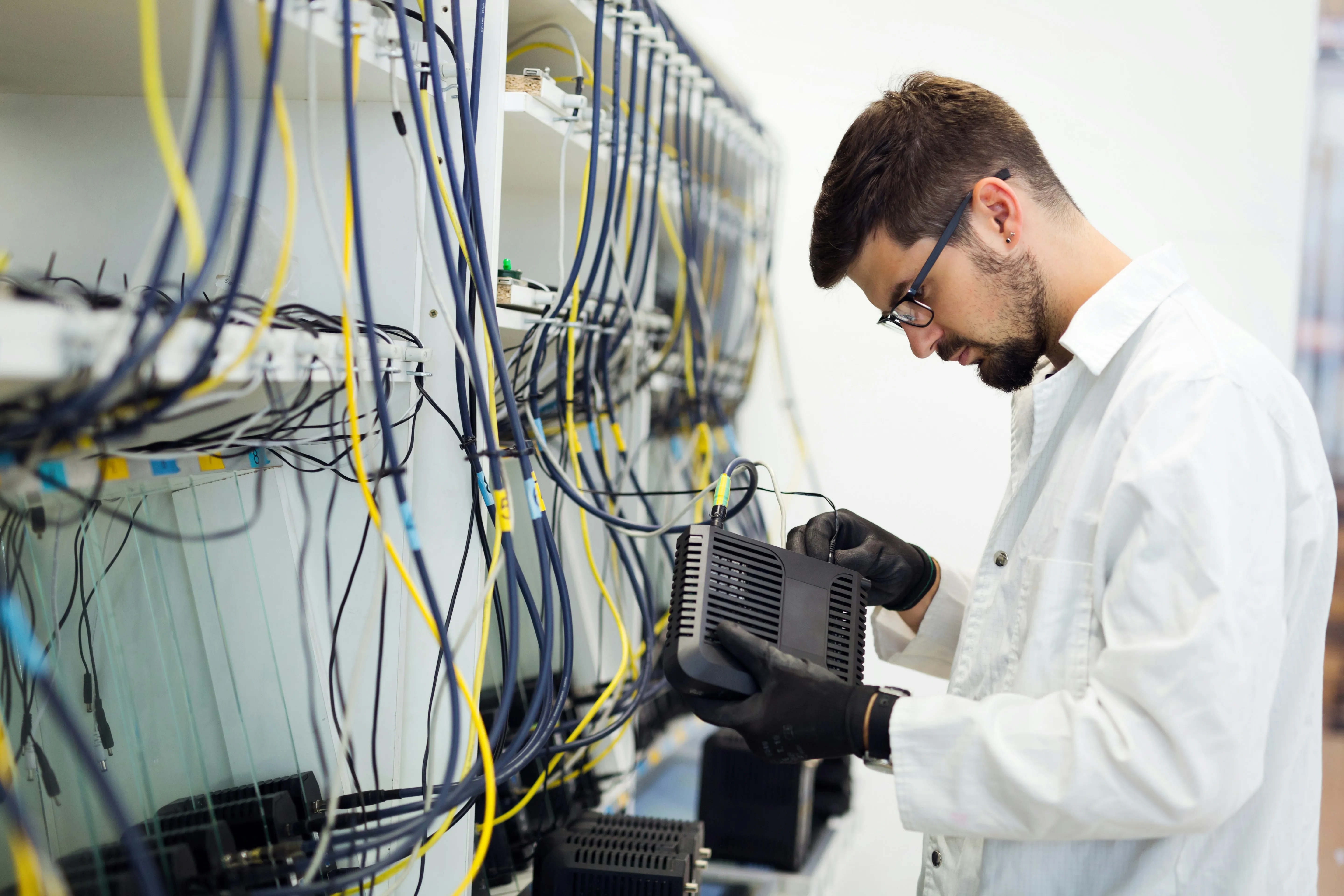 An electrician carefully installing or maintaining data cabling and network infrastructure for commercial or industrial clients.
