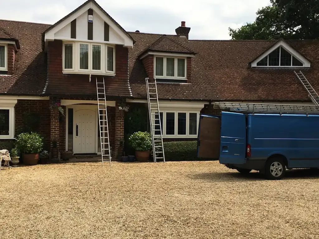 House with ladders against the roof and a blue van, showing a domestic property ready for roofing work.