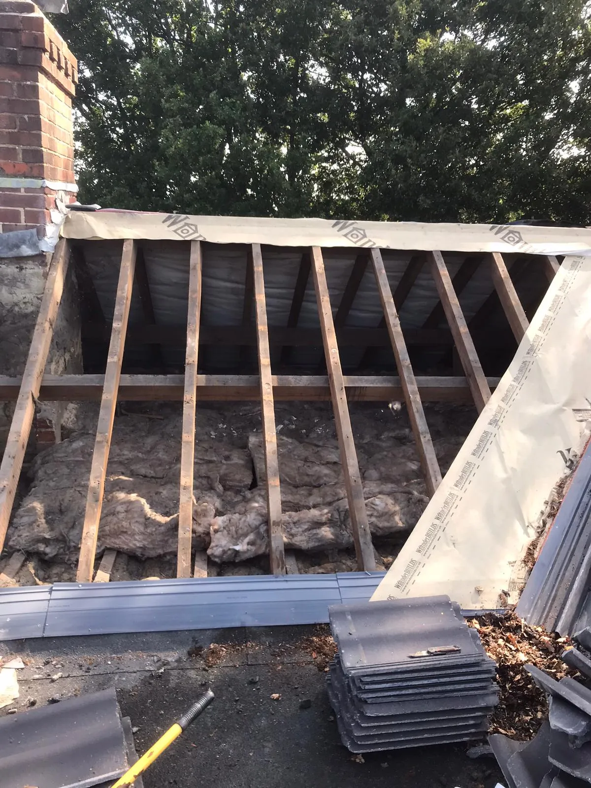 Roof insulation and timber rafters visible during a roof installation or repair project by Storm Guard Solutions.