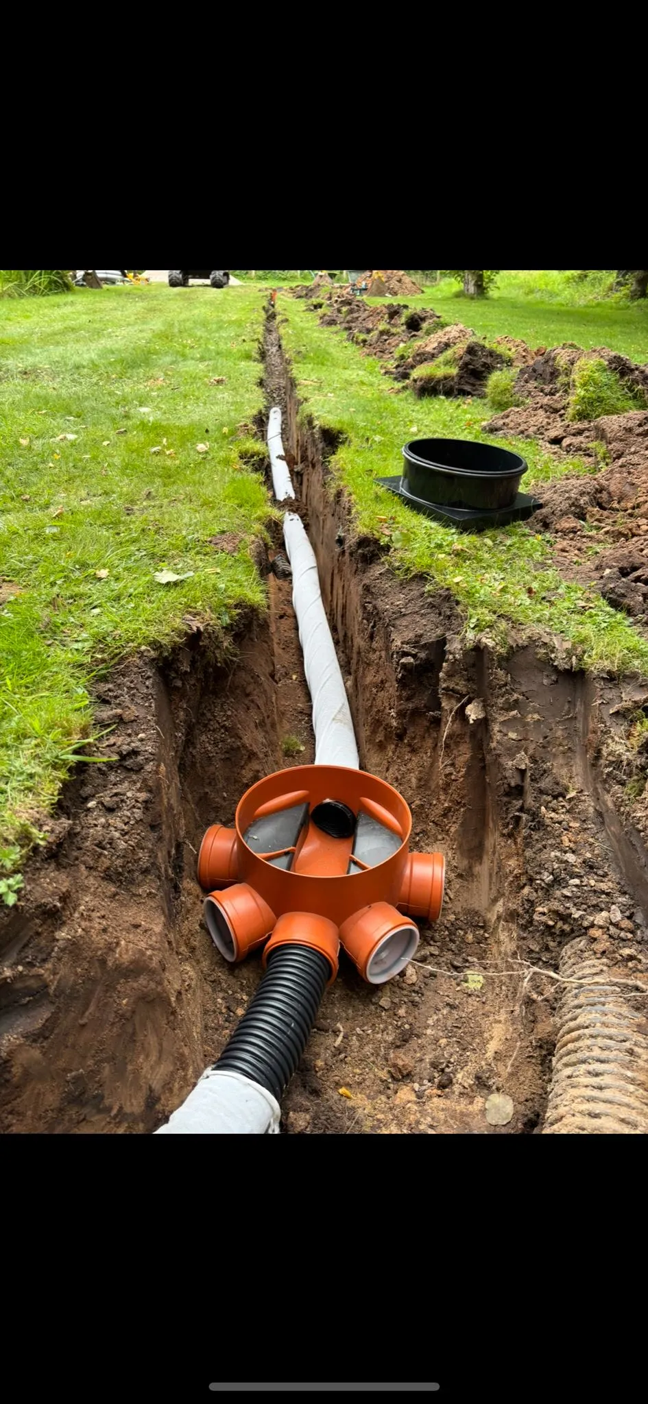 Drainage pipes and a junction box in an open trench during installation or repair work.