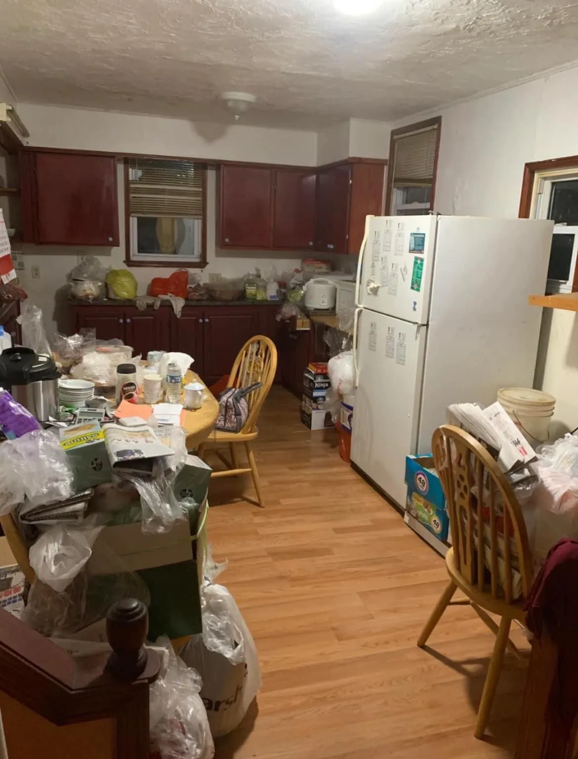 A severely cluttered kitchen filled with rubbish, bags, and items, illustrating a property requiring a hoarder clearance service.