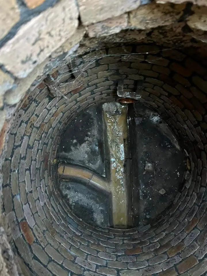 Inside a brick drainage manhole with channels and water.