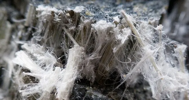 Close-up detail of white fibrous asbestos material requiring testing.