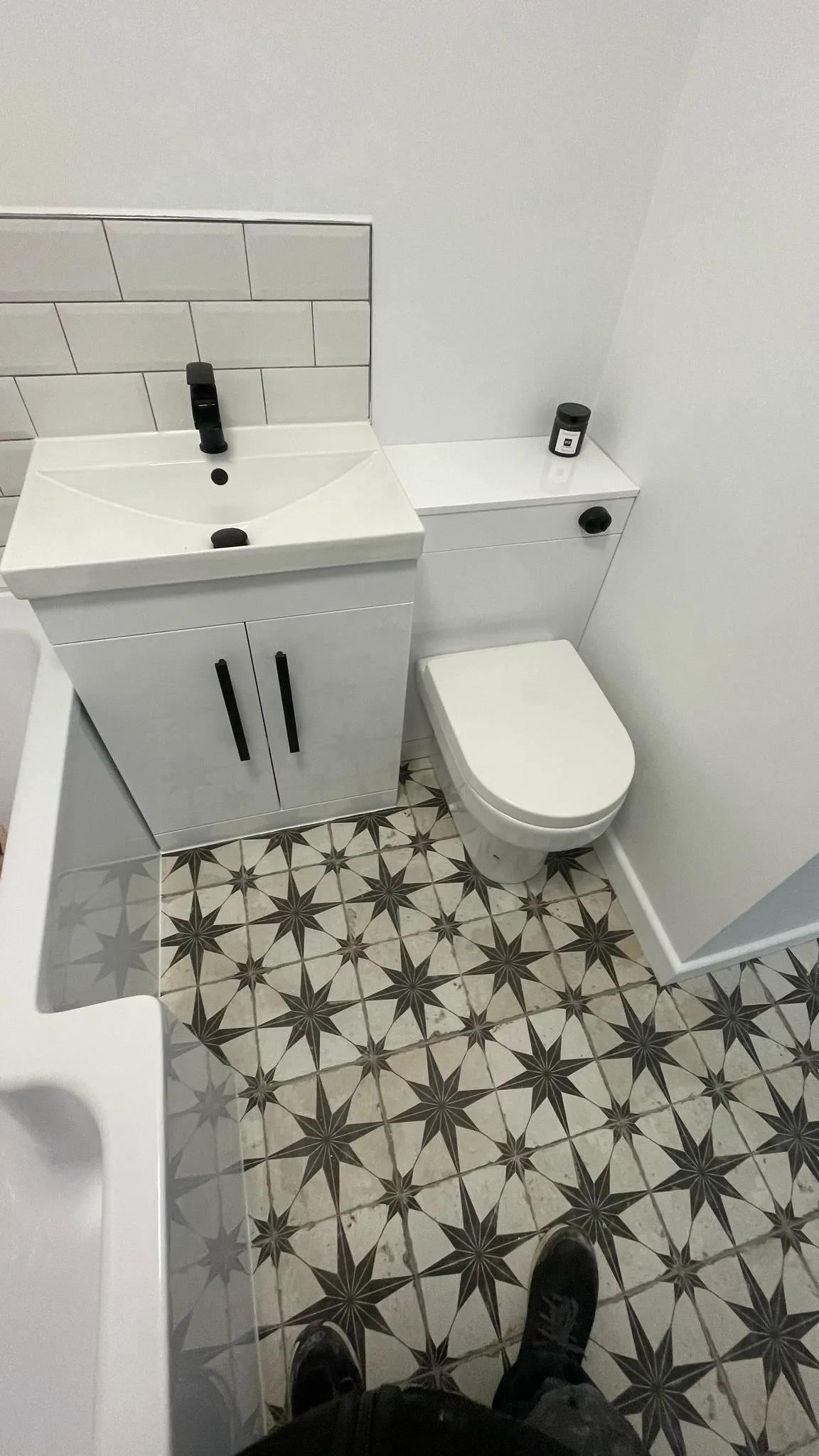 A professional bathroom renovation in Cheltenham showing a new sink, toilet, and patterned tiling.