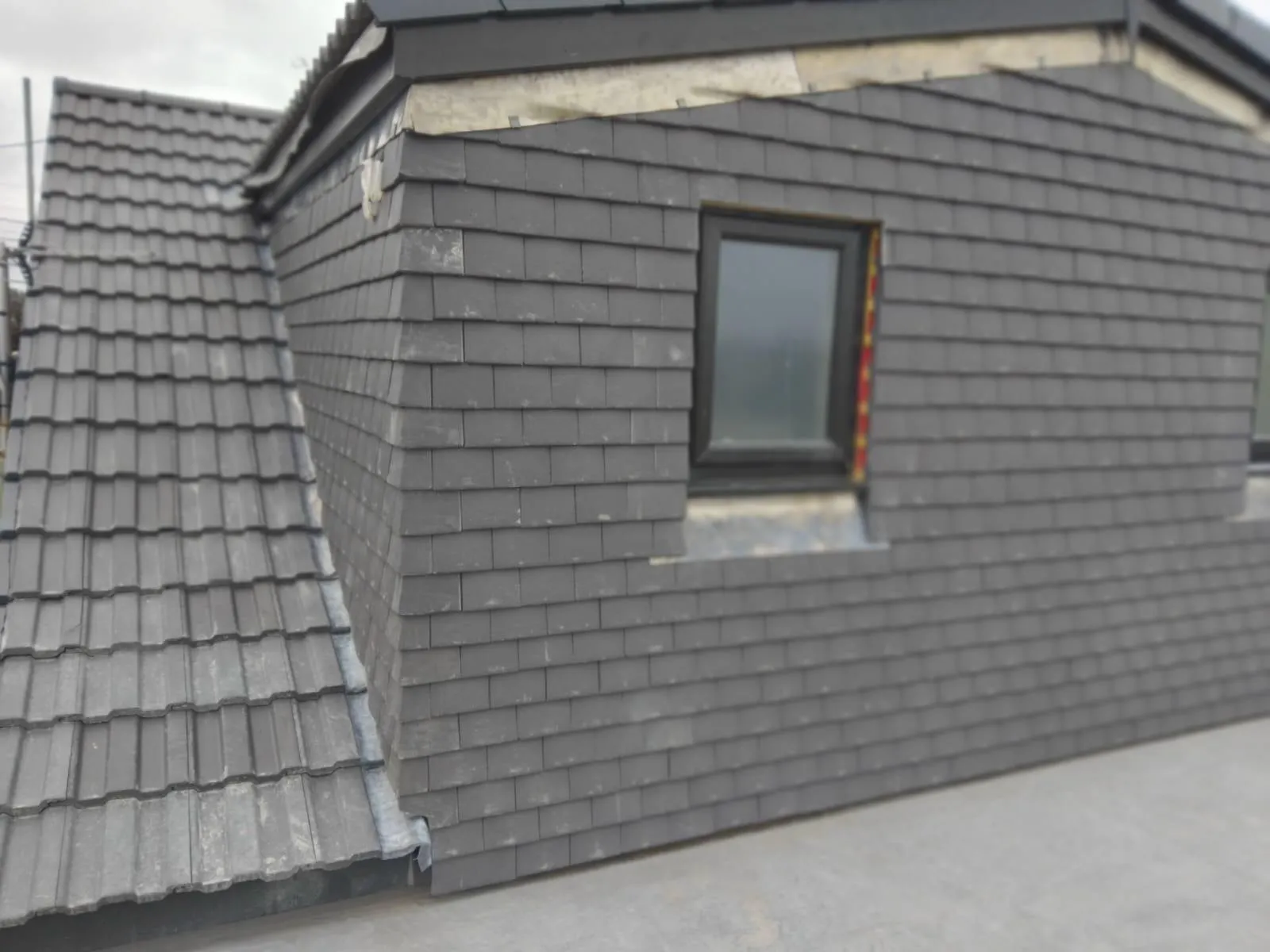 New dormer window with dark grey slate cladding and a tiled roof section.