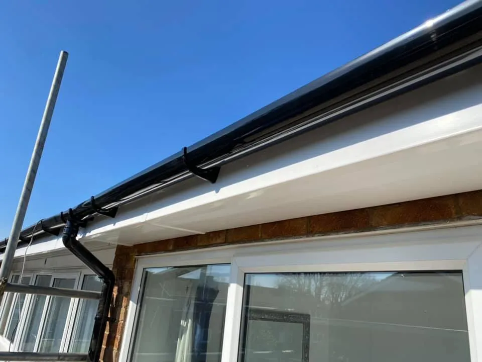 Newly installed black uPVC guttering, white fascias, and soffits on a house roofline.