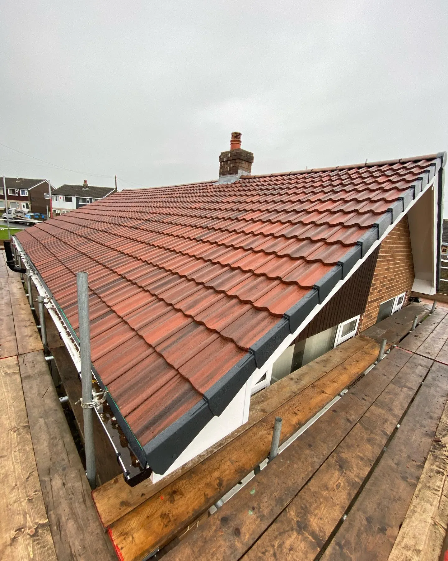 Newly tiled roof replacement on a bungalow with scaffolding by Toptile Roofing.