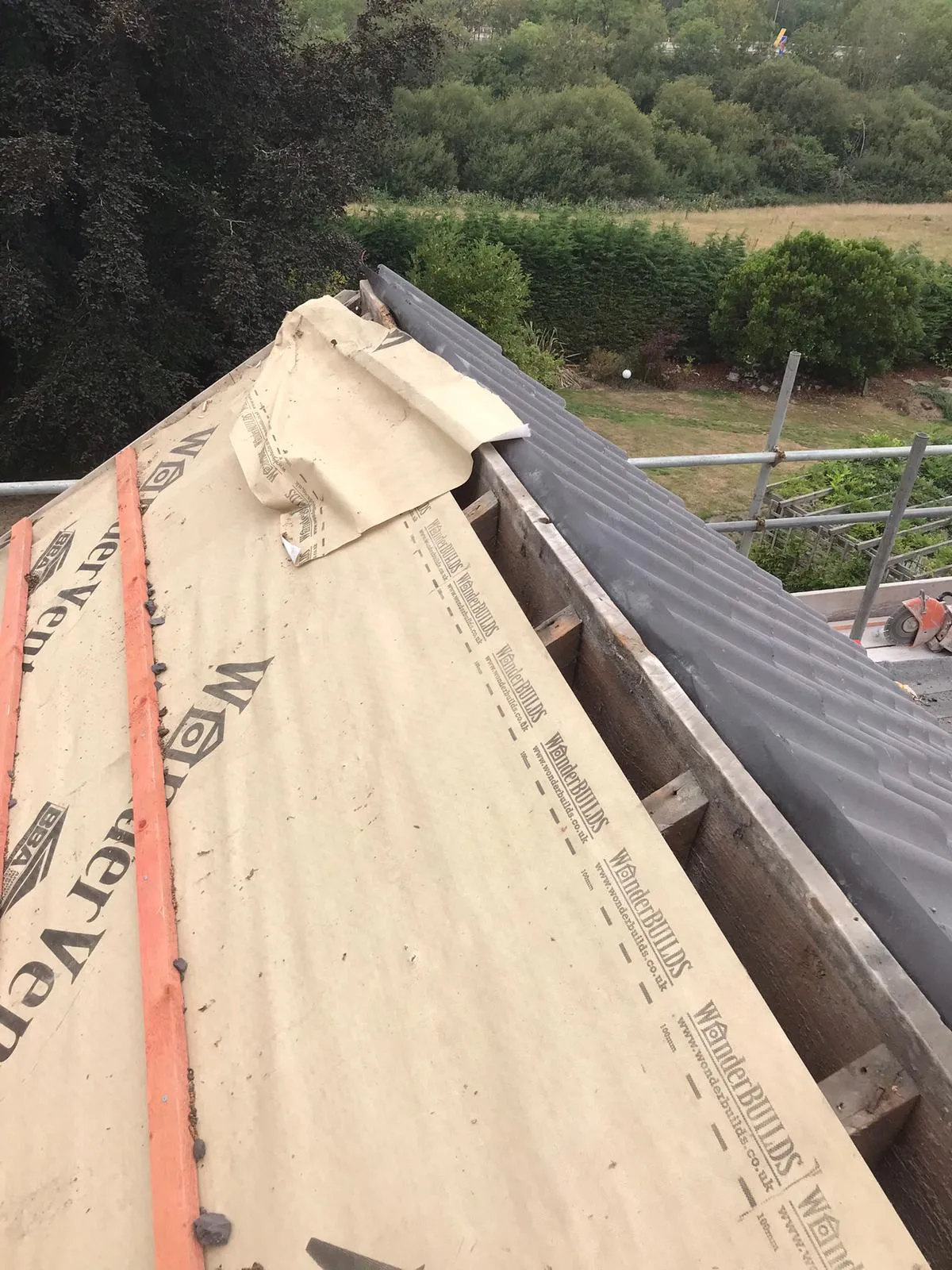 Pitched roof installation in progress, with underlayment and new roof tiles being laid.