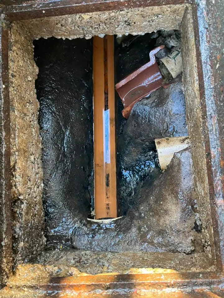 Blocked drain manhole with murky water and debris