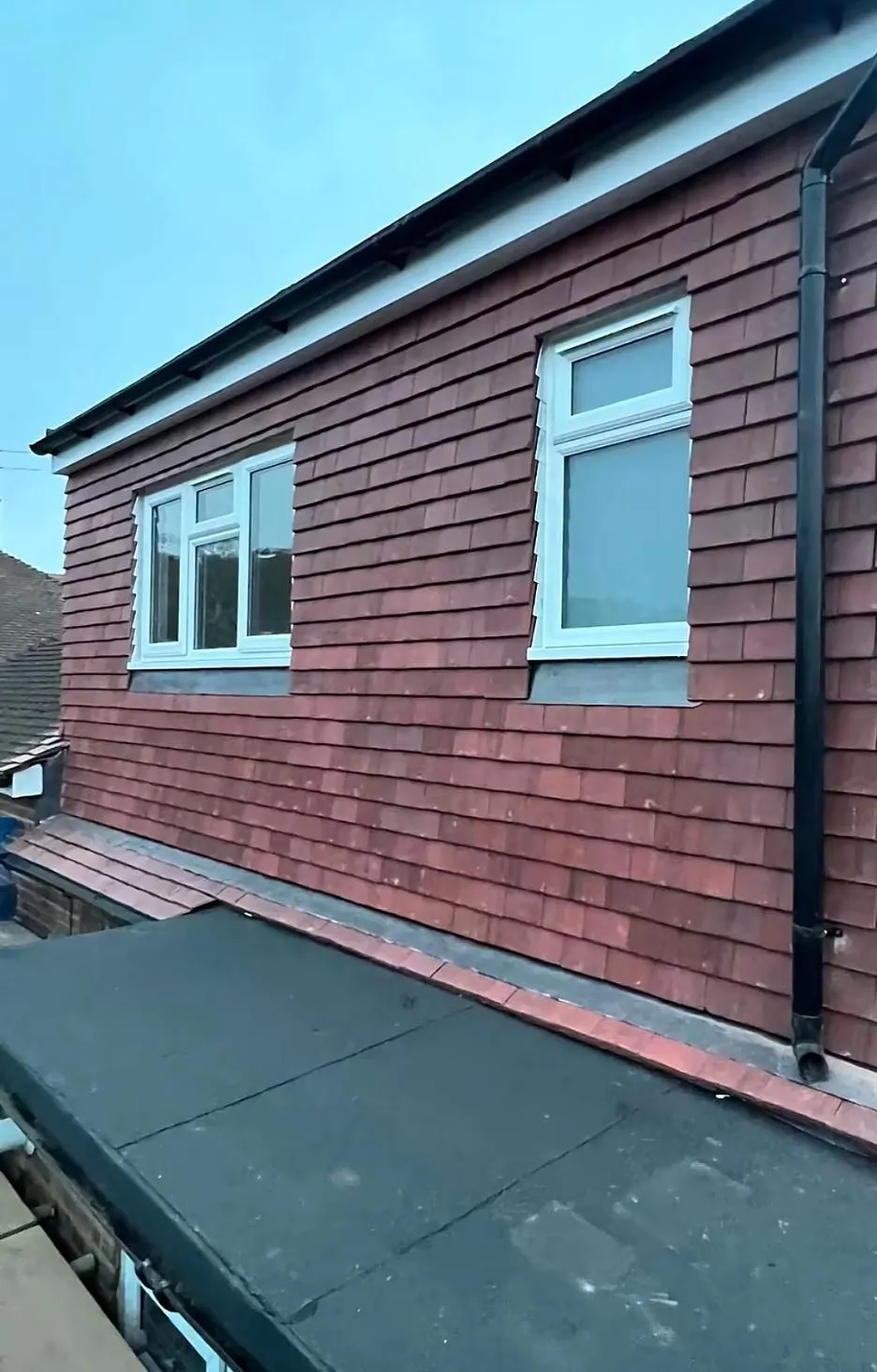 Newly completed dormer extension with red tile cladding and flat roof